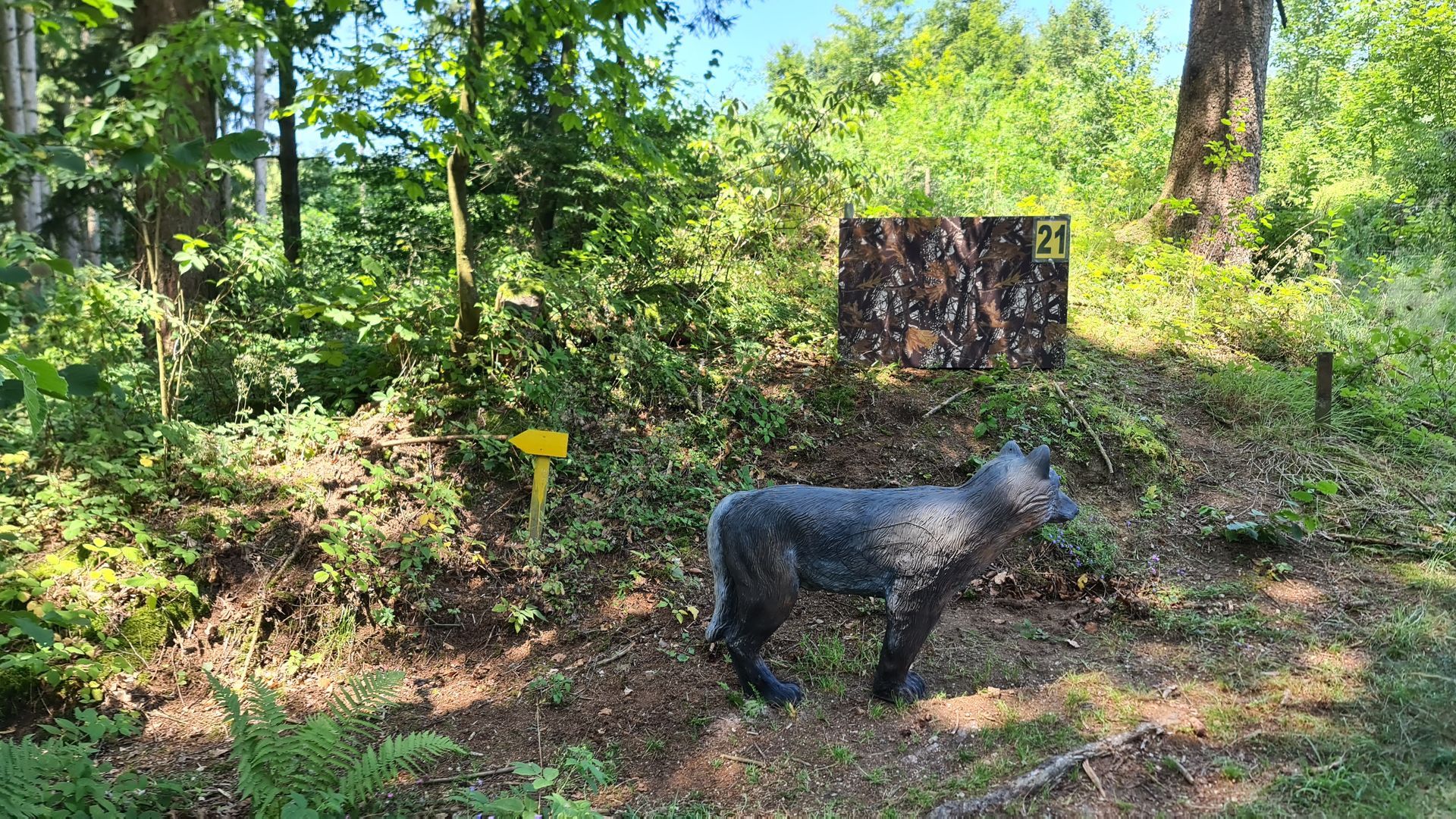 Bogenschießziel in Wolfsform in einem Waldgebiet mit gelbem Wegweiser.