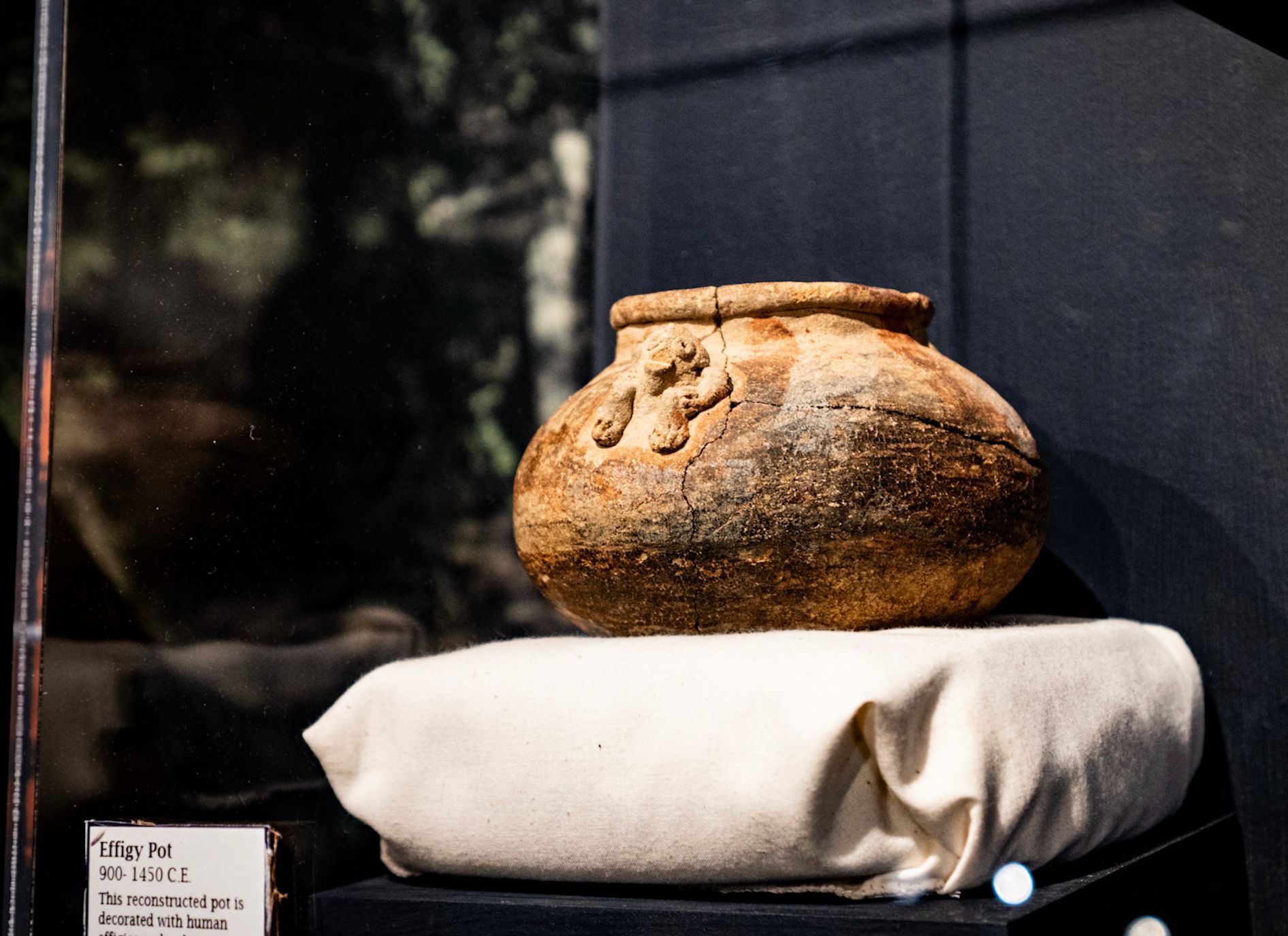 Ancient ceramic jar on a white cushion in a display case