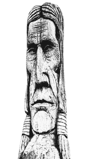 Black-and-white carved face on a tall stone totem or statue, shown close up against a plain background.