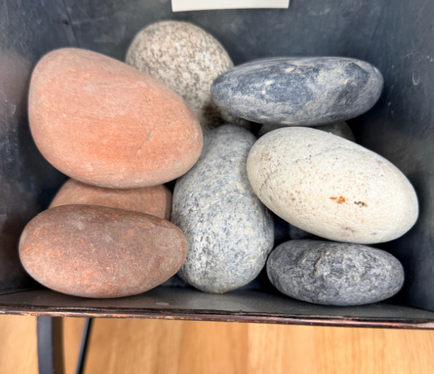 A collection of smooth, multi-colored river stones arranged in a dark container.