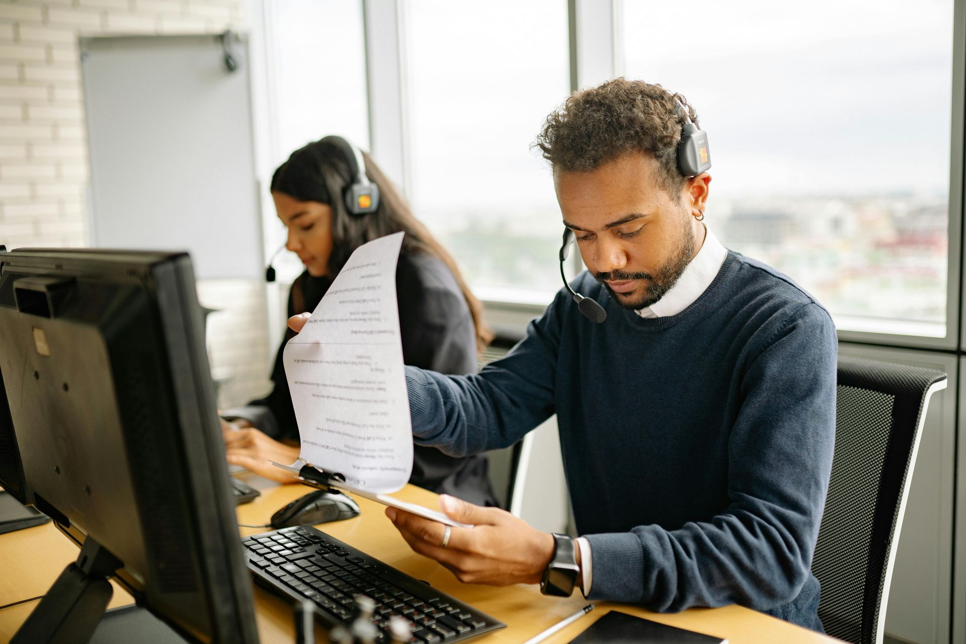 Two coworkers reviewing documents at a desk in a bright office