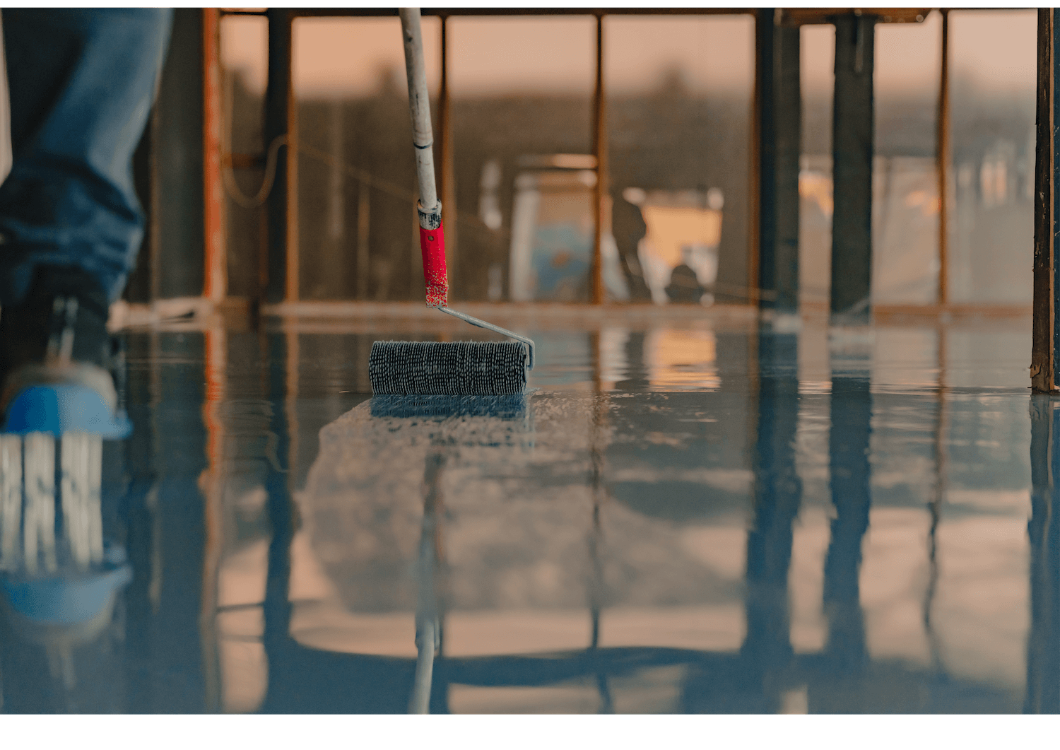 Floor squeegee moving water across a glossy indoor surface in a bright room