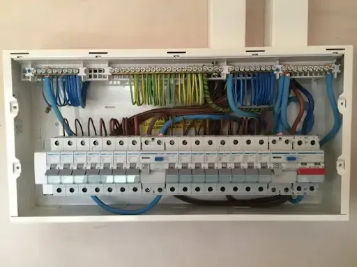 Electrical panel with blue, brown, yellow, and green wires connected to circuit breakers and terminals.