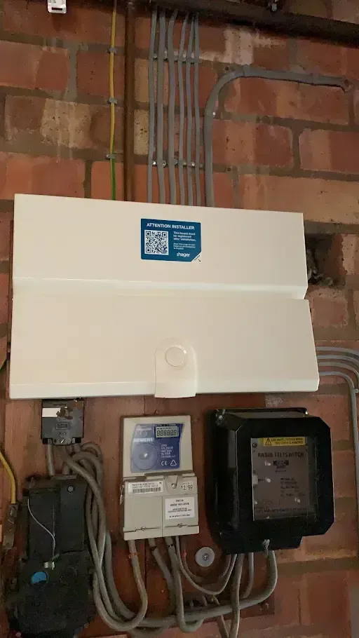 Residential electrical control panel and meter boxes mounted on a brick wall.