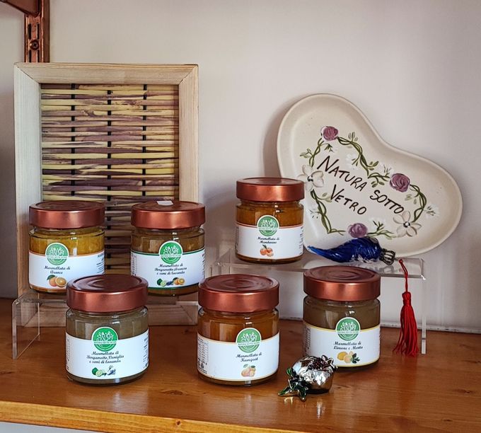 Prodotti erboristici in barattolo su uno scaffale di legno con un cartello decorativo e un cestino sullo sfondo.