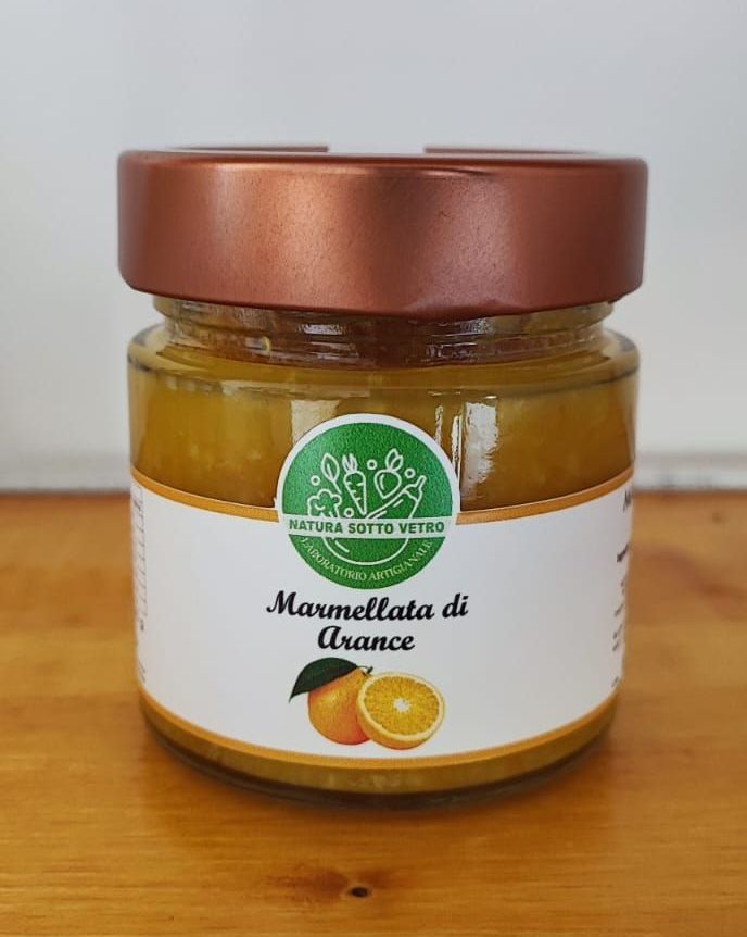 Un barattolo di marmellata d'arance con coperchio di rame su un tavolo di legno, con l'etichetta