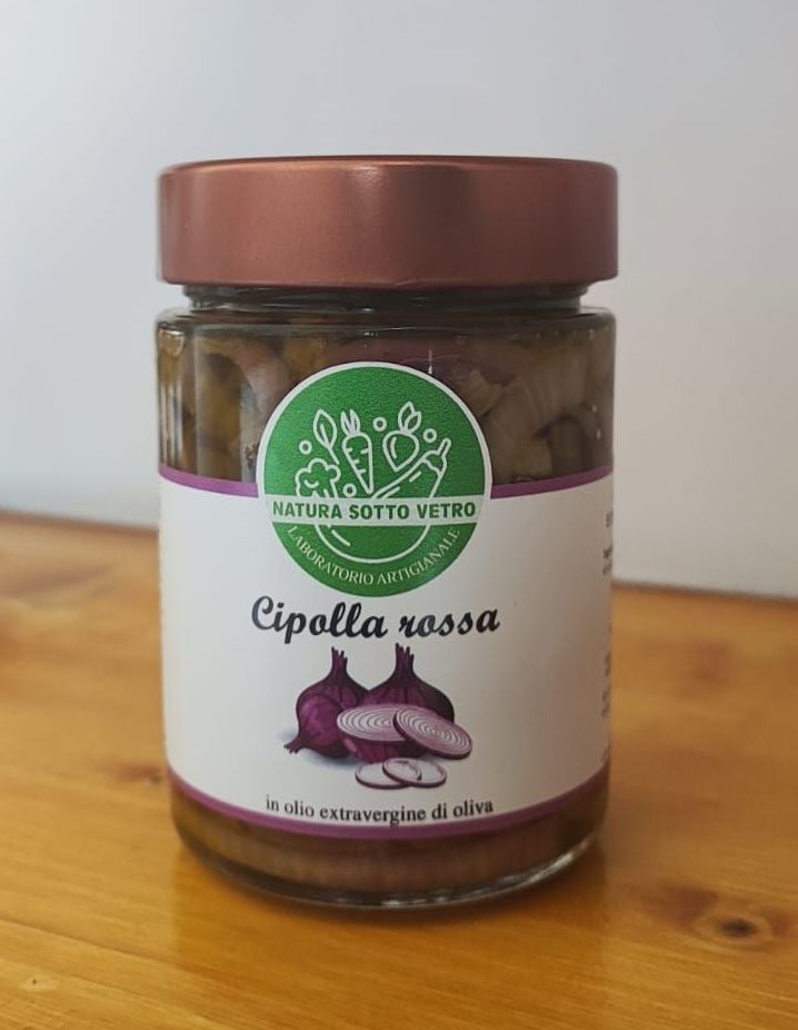 Un barattolo di crema di cipolle rosse con coperchio marrone ed etichetta verde su un tavolo di legno.