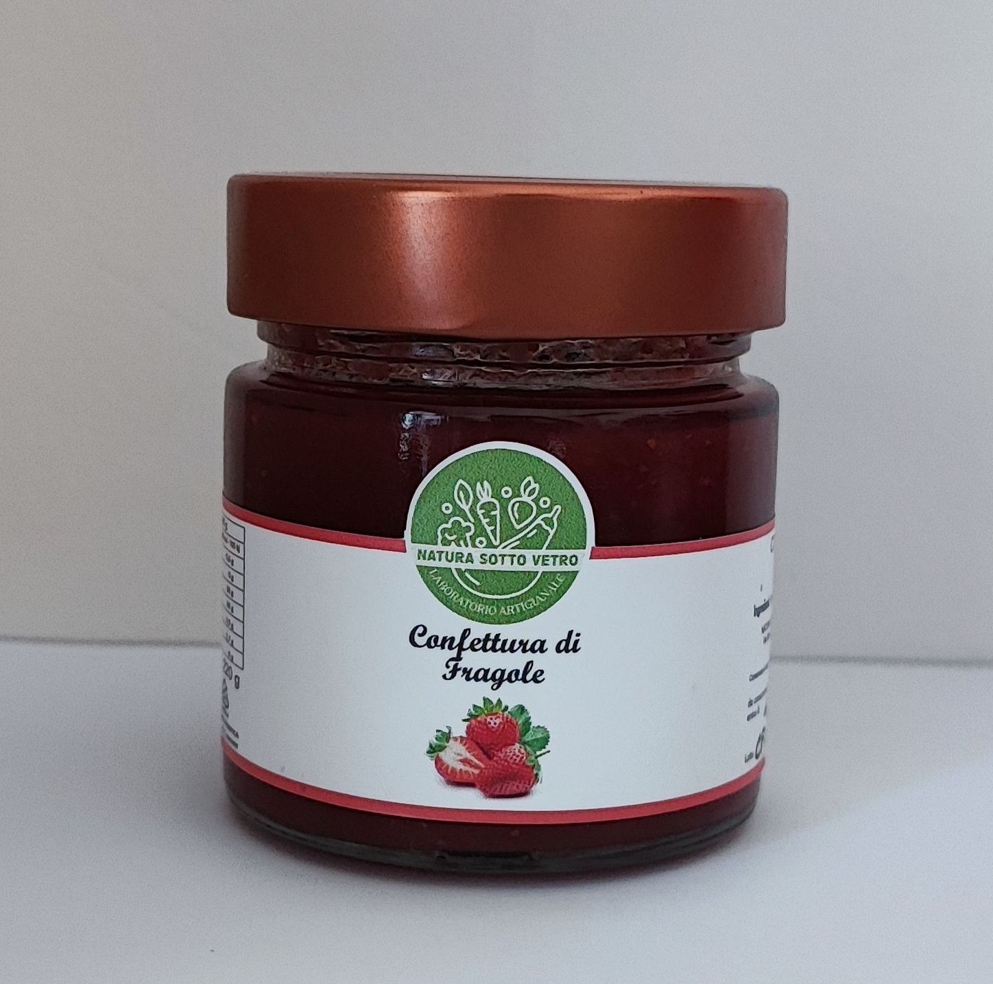 Barattolo di marmellata di fragole con coperchio marrone ed etichetta bianca su sfondo neutro.