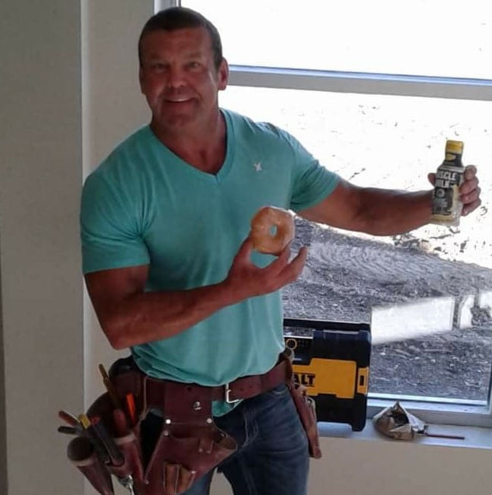 a man in a blue shirt is holding a donut and a bottle