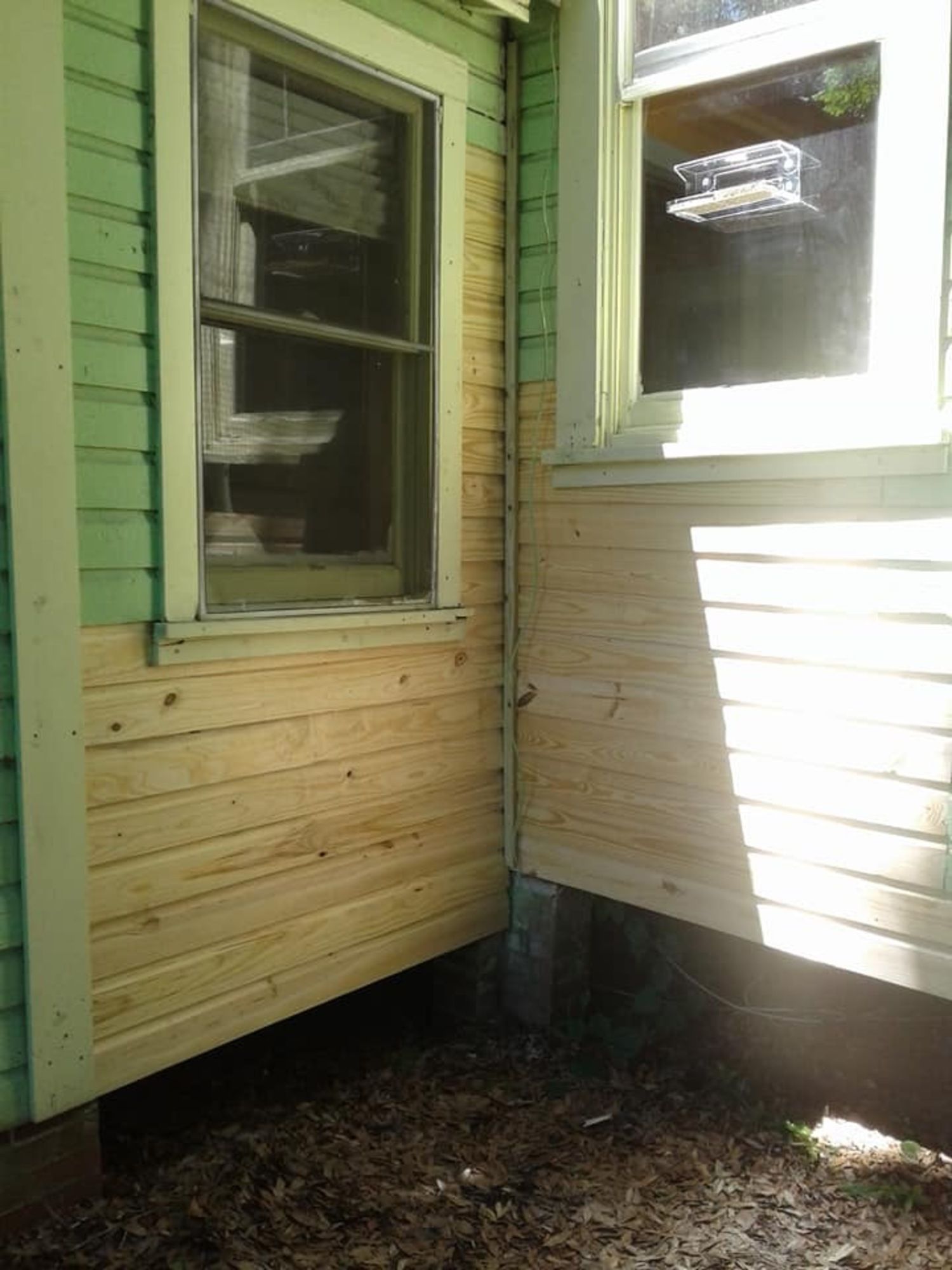 a green and white house with a wooden siding and a window