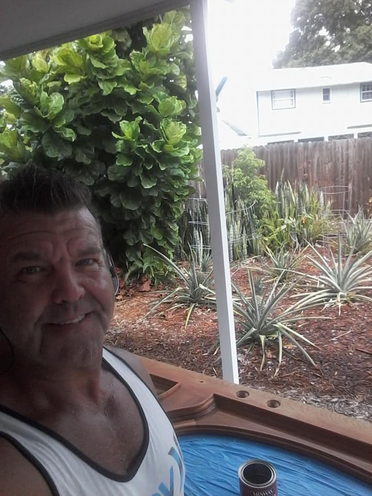 a man in a white tank top is standing on a porch