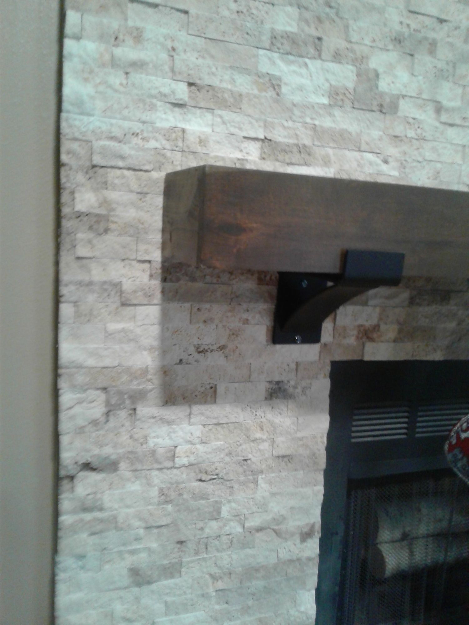 a fireplace with a wooden mantle and a brick wall behind it .