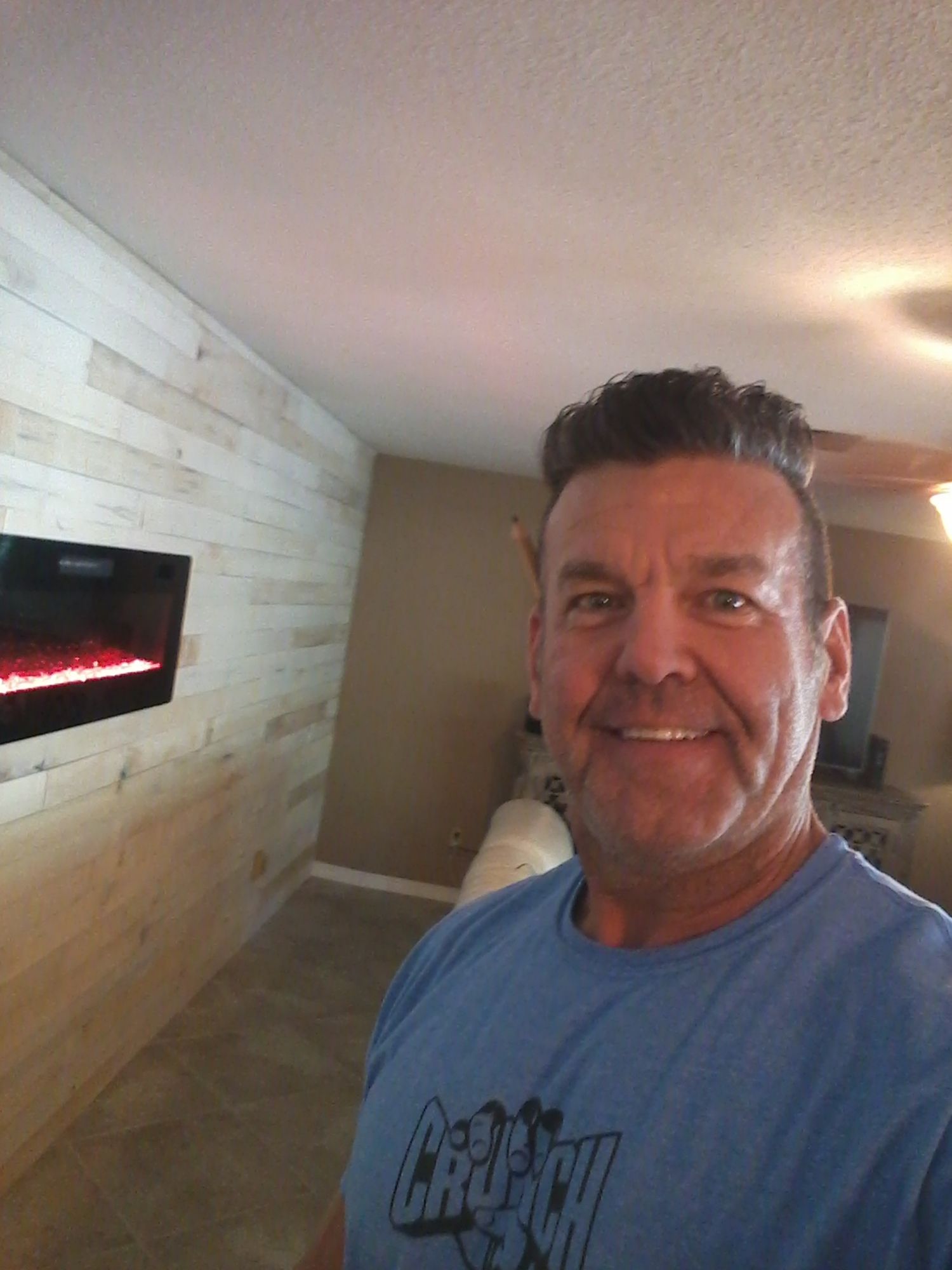 Patrick the owner is standing in a living room in front of a newly installed fireplace