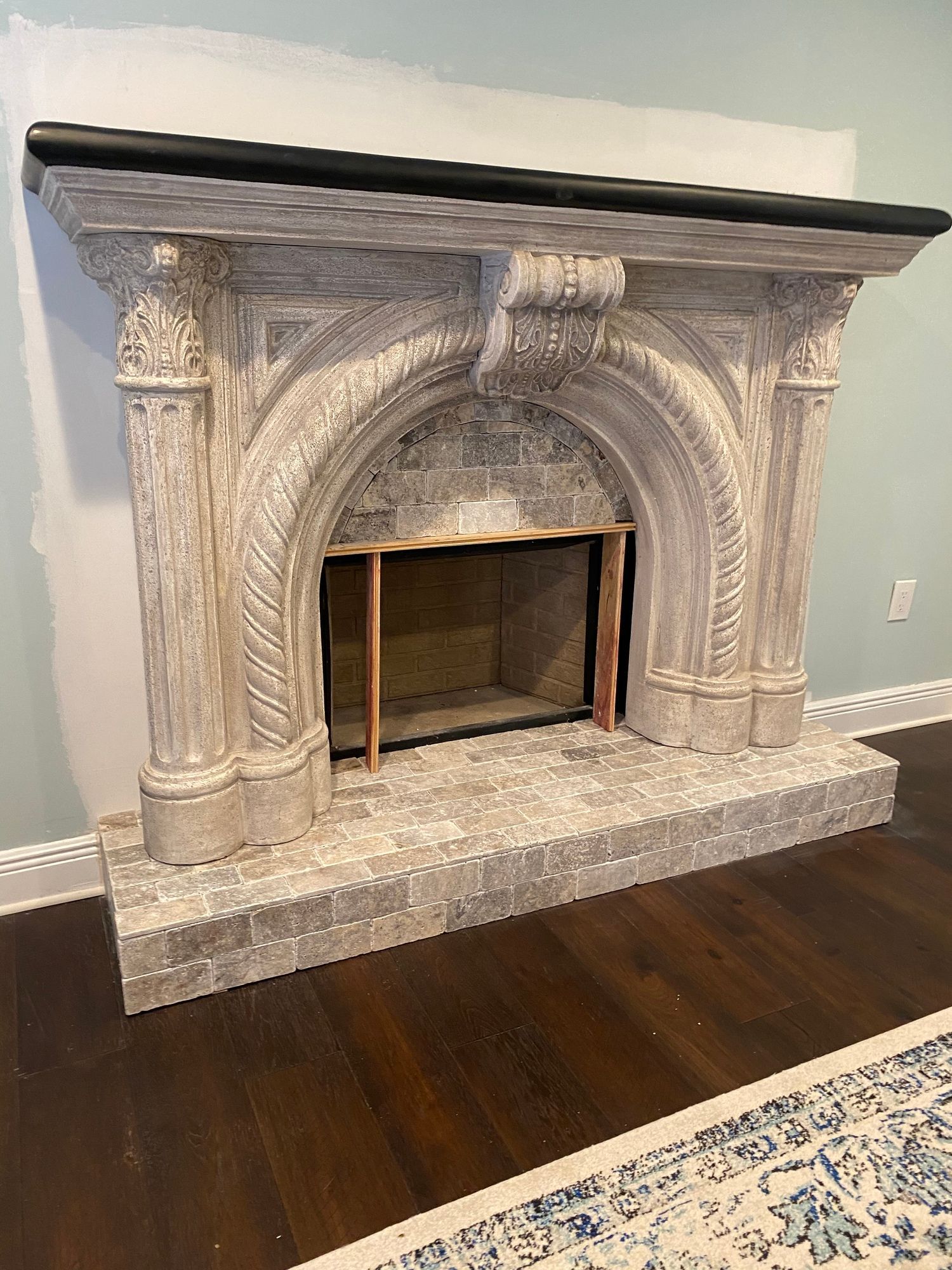 a fireplace is sitting in a living room next to a rug .
