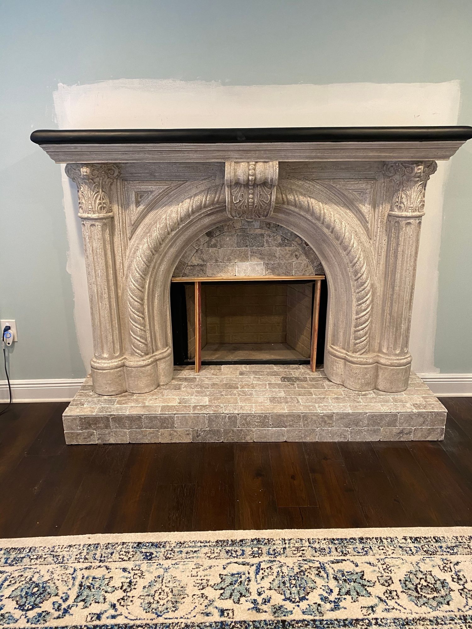 a fireplace is sitting in a living room next to a rug .