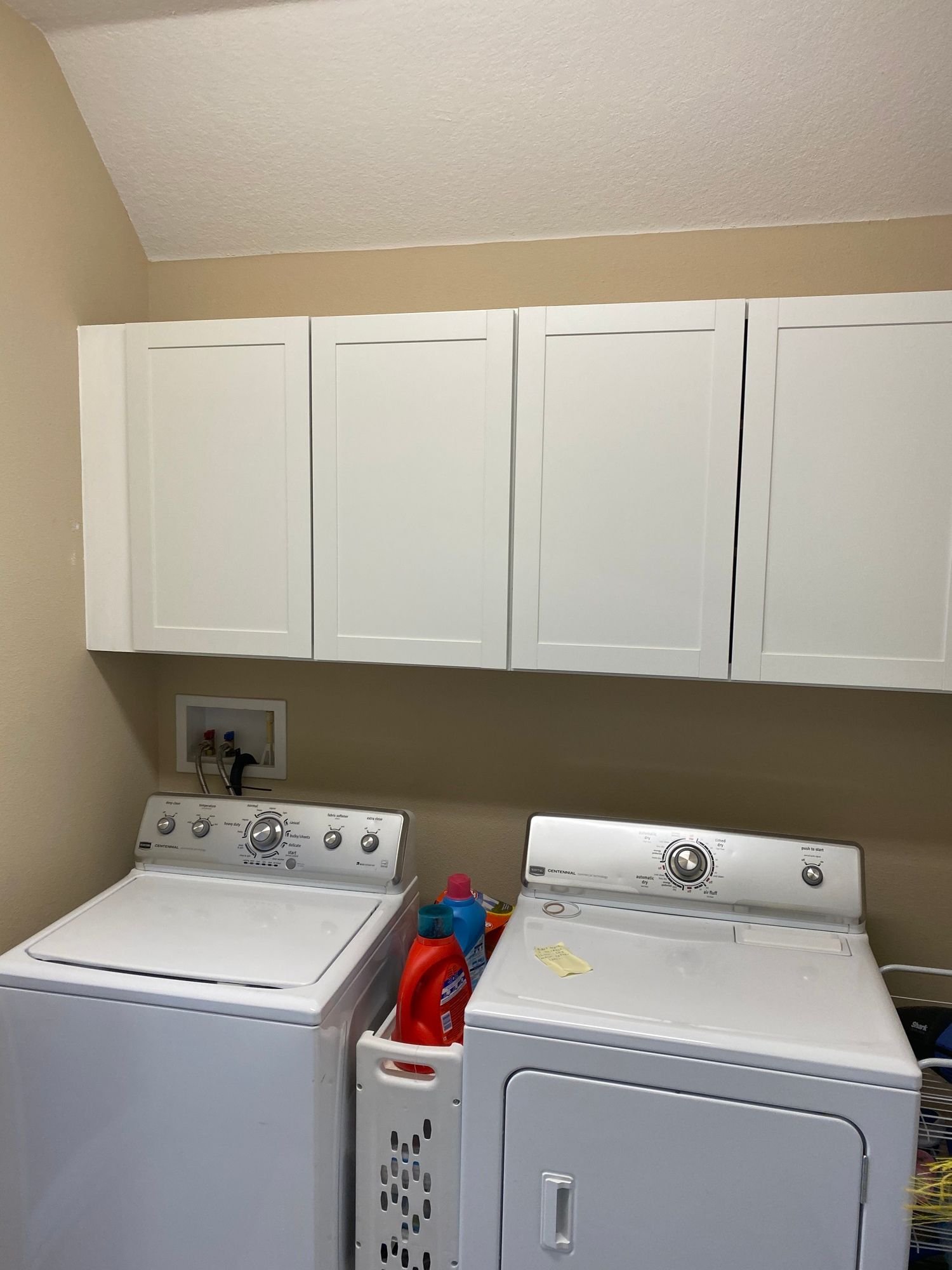 a laundry room with a washer and dryer and white cabinets .