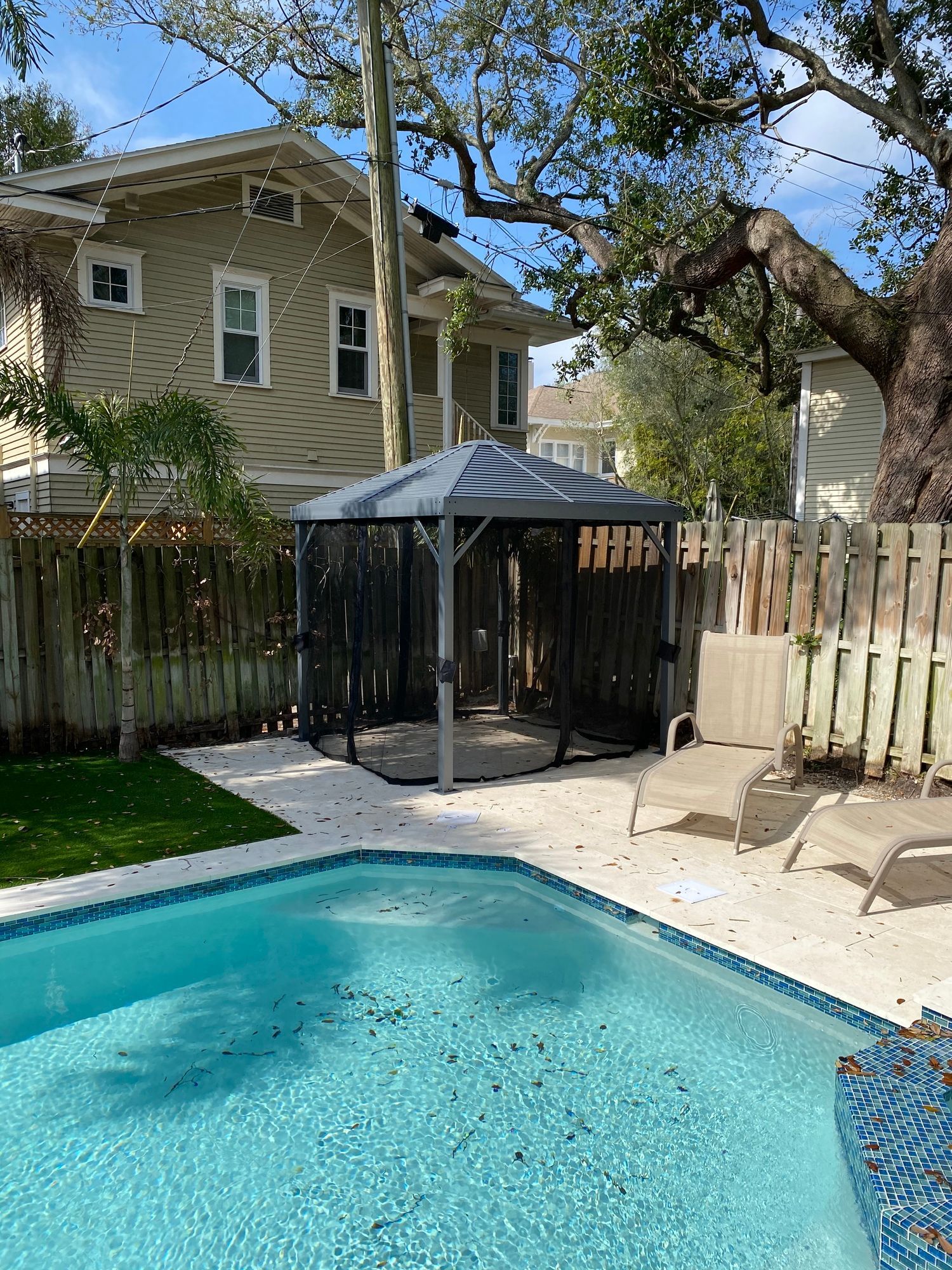 a large swimming pool with a gazebo in the backyard of a house .