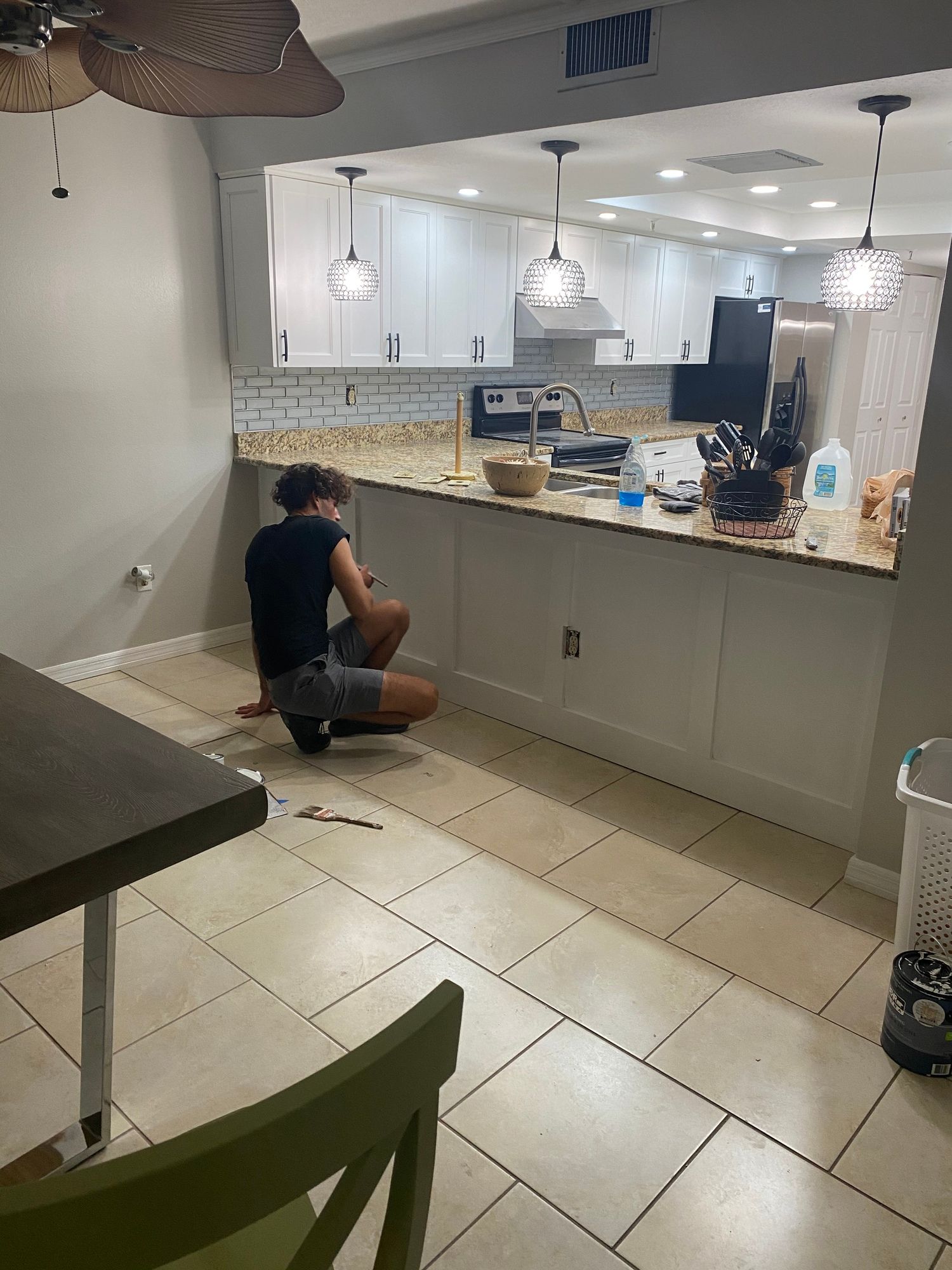 a woman is kneeling on the floor in a kitchen .