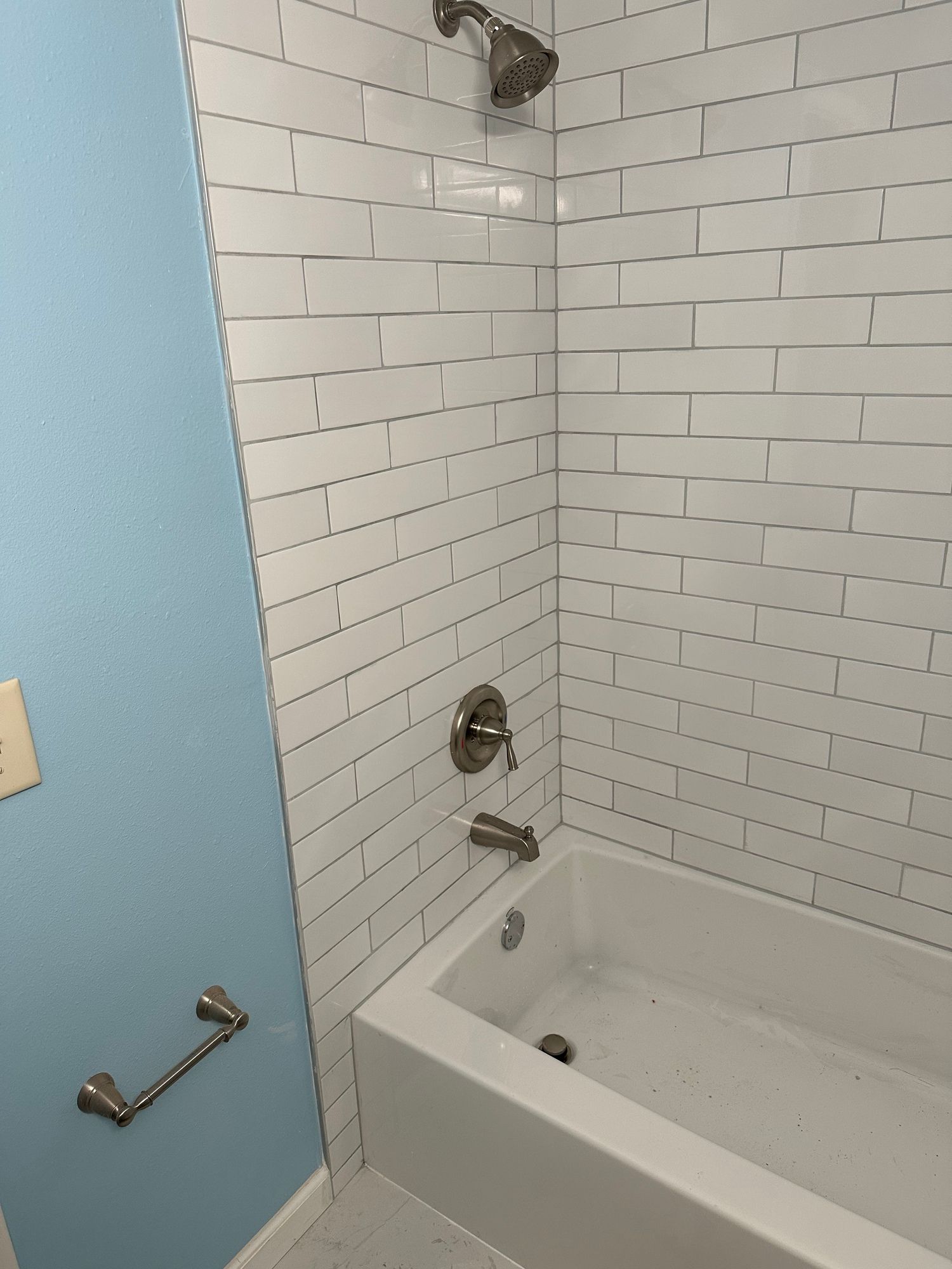 a bathroom with white brick tiles and a bathtub