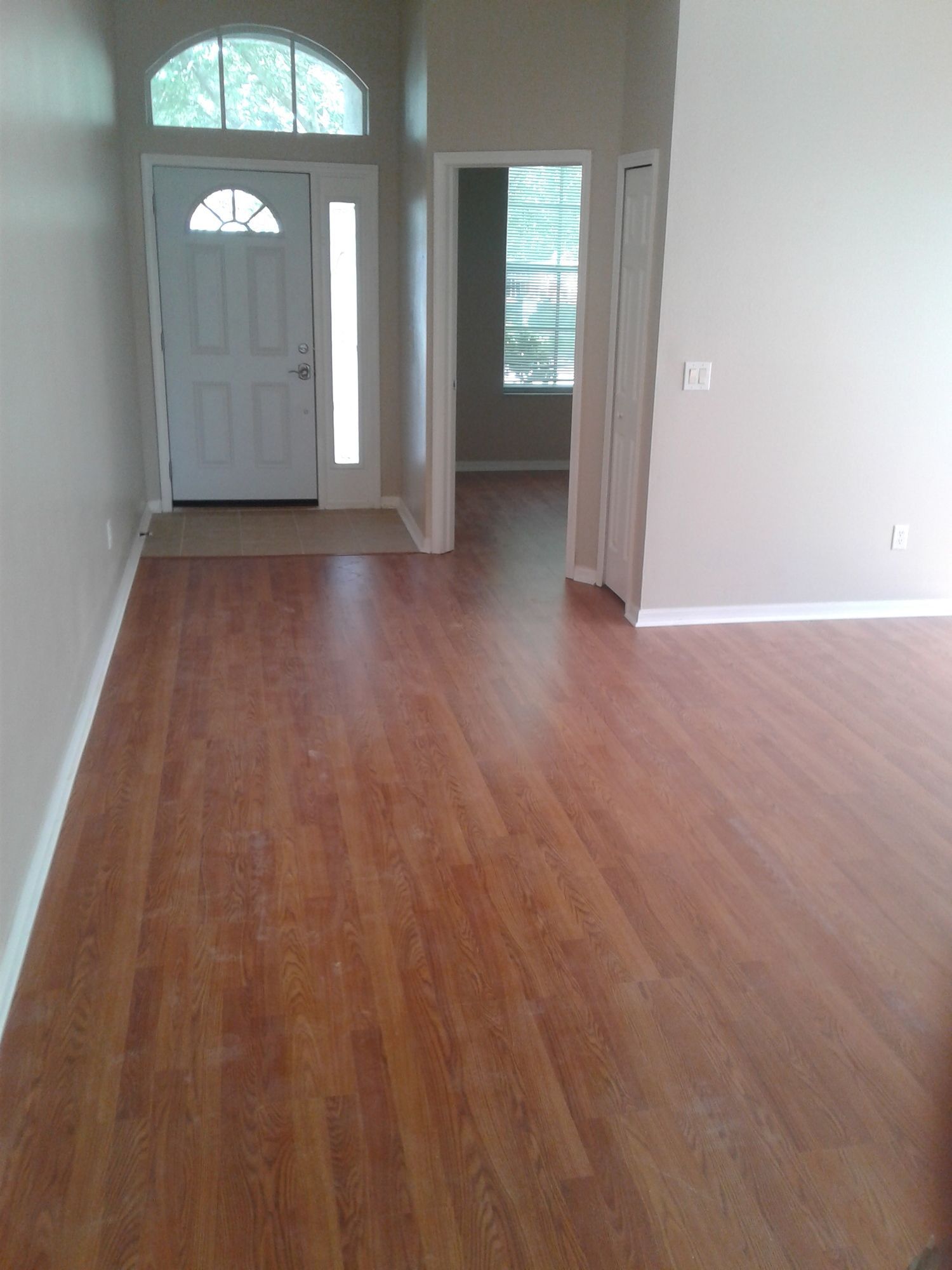 an empty living room with hardwood floors and a white door .