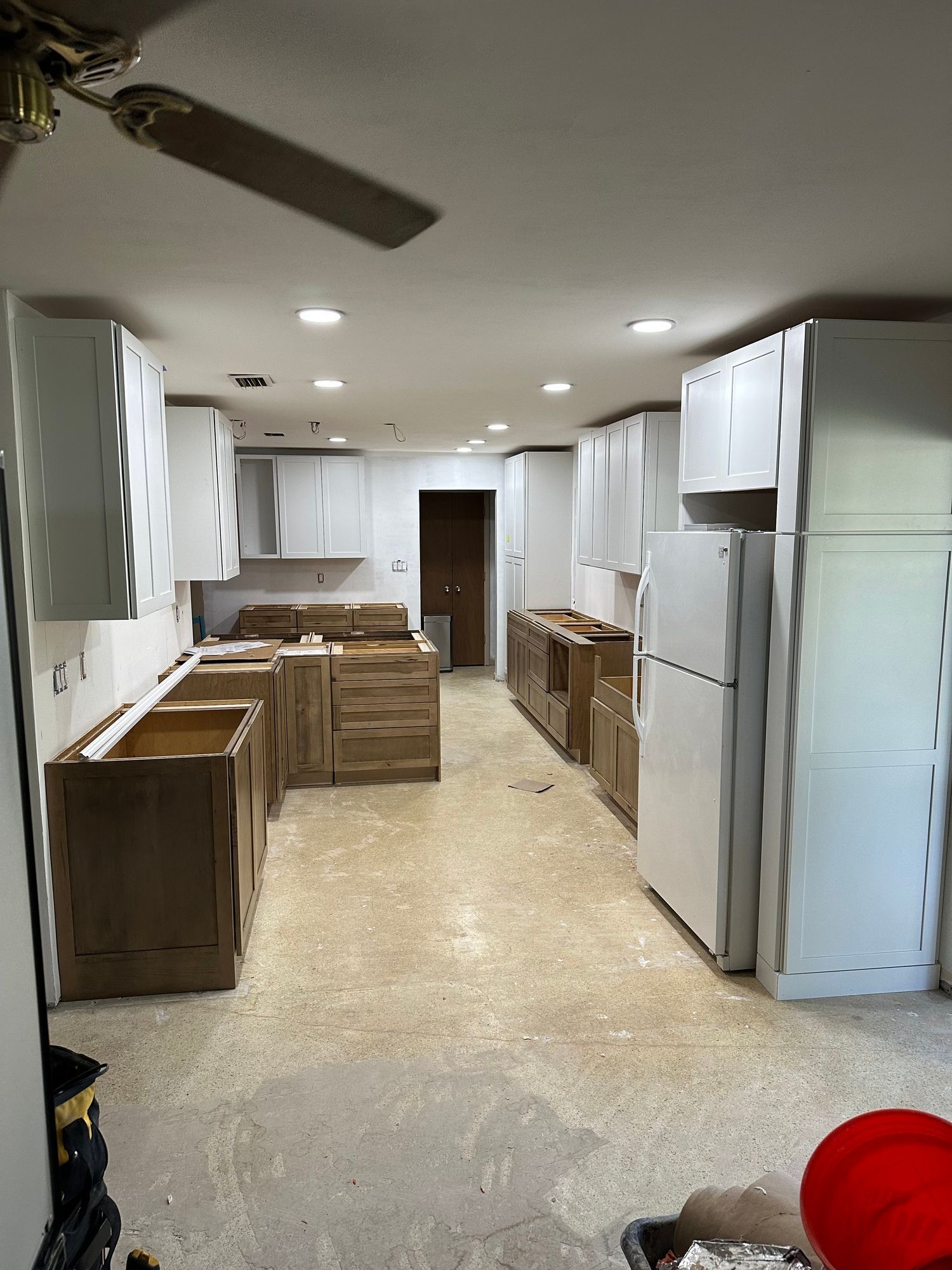 a kitchen under construction with white cabinets and a refrigerator .