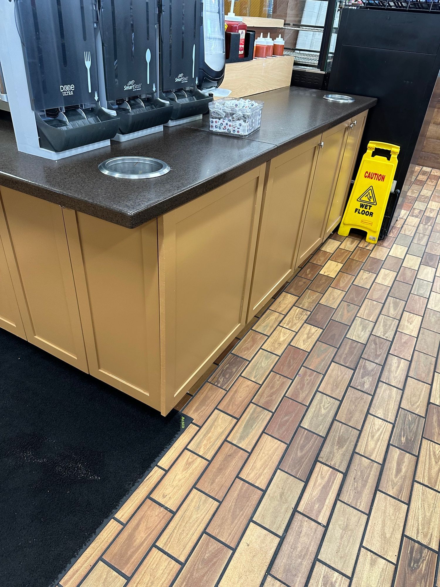 a yellow caution sign is next to a counter in a restaurant .