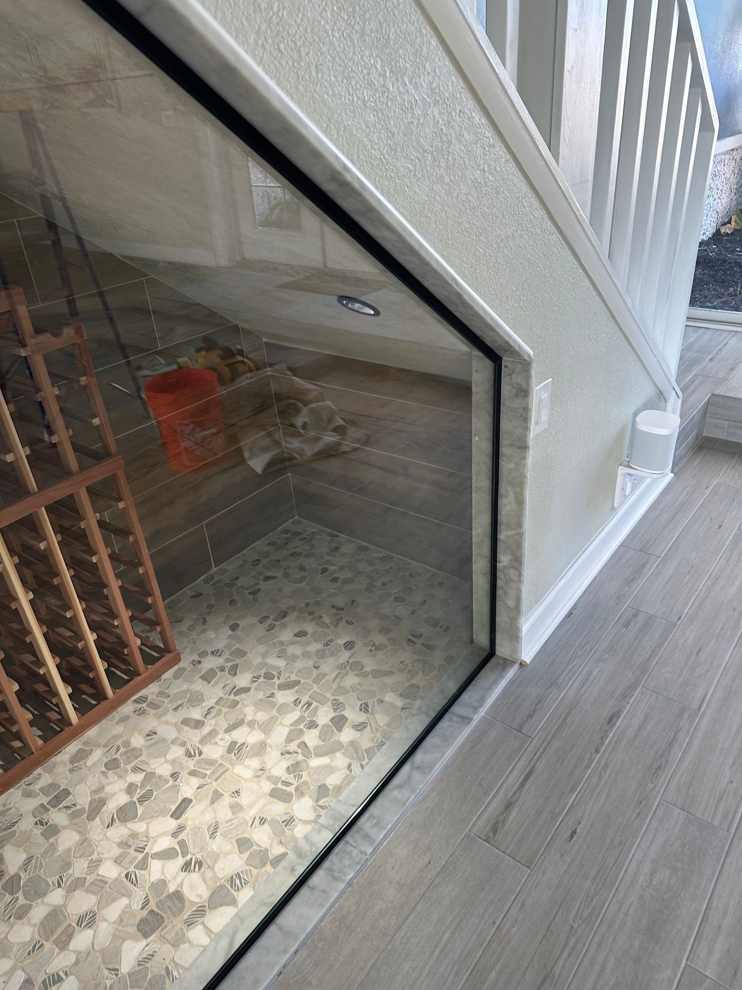 a wine cellar under a staircase with a glass door .