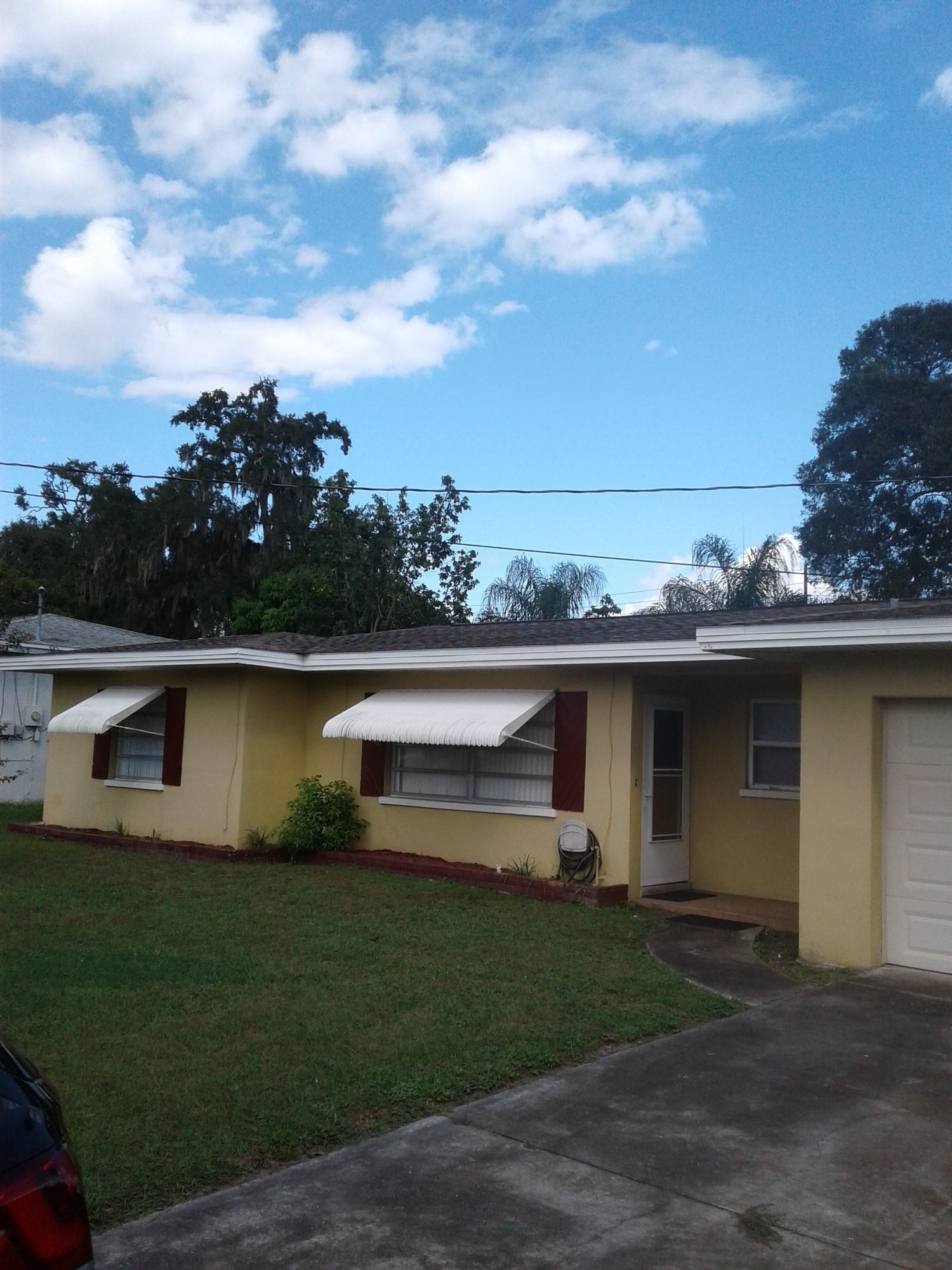 a yellow house with white awnings on the windows