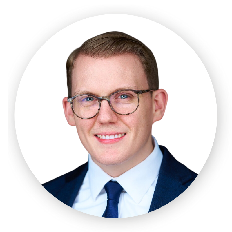 A man wearing glasses and a suit is smiling for the camera