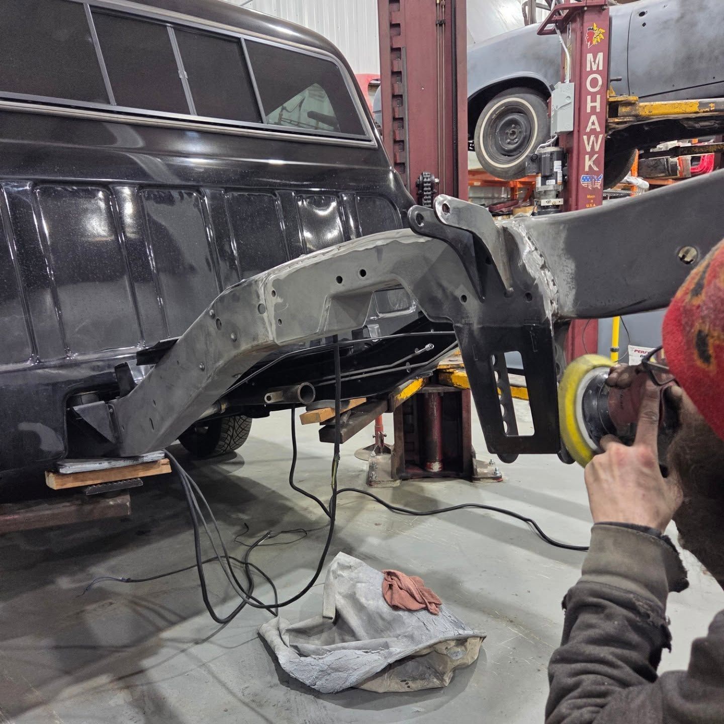 A man is polishing a car with a mohawk sign in the background