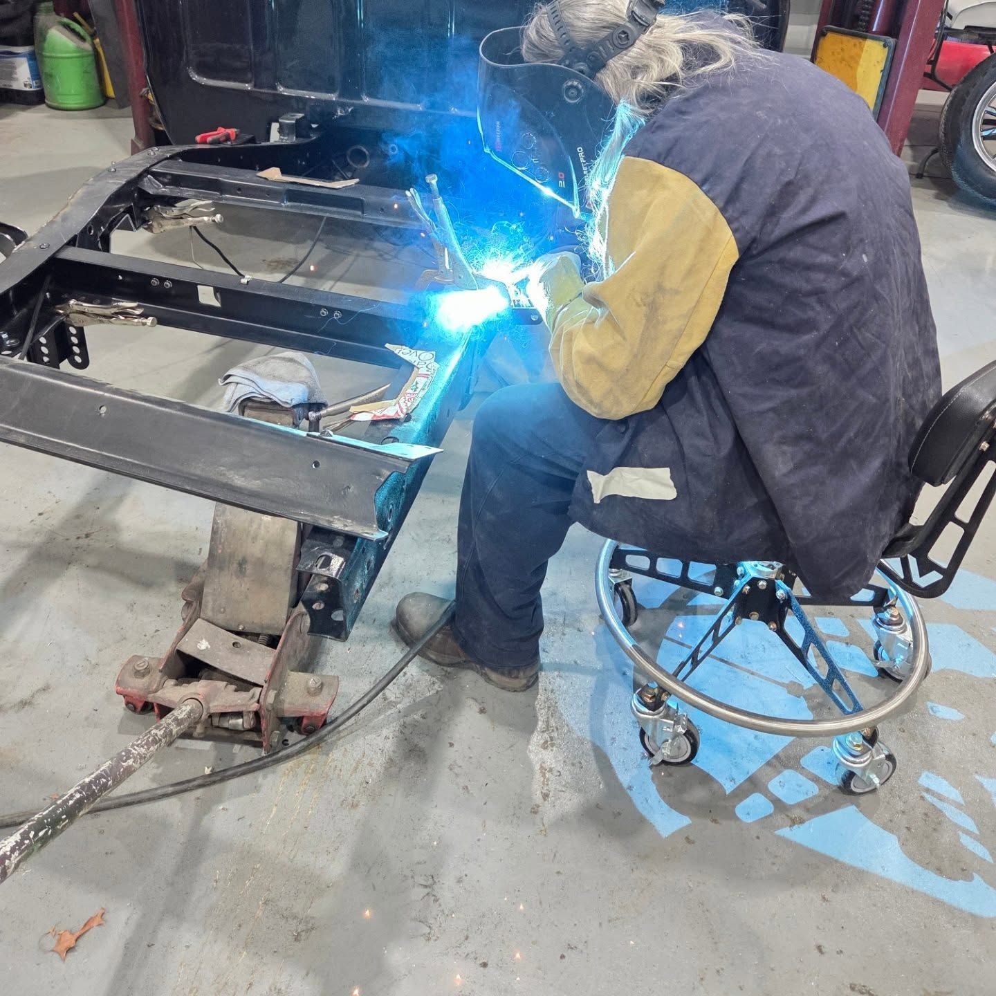 A man is welding a piece of metal in a garage