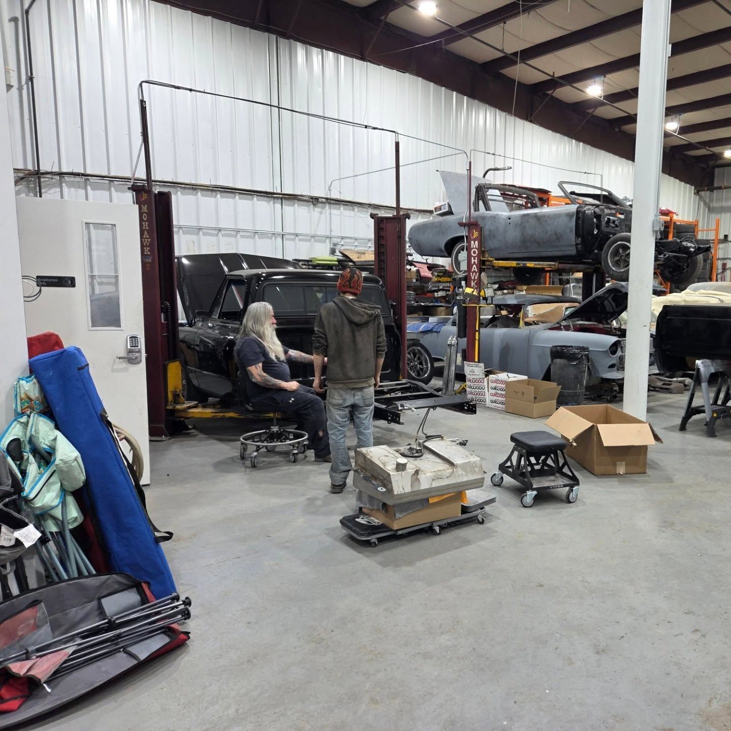 A man is standing in a garage talking to another man