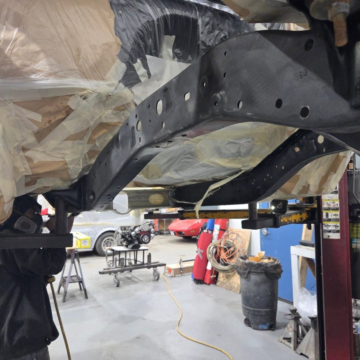 A man is working underneath a car in a garage