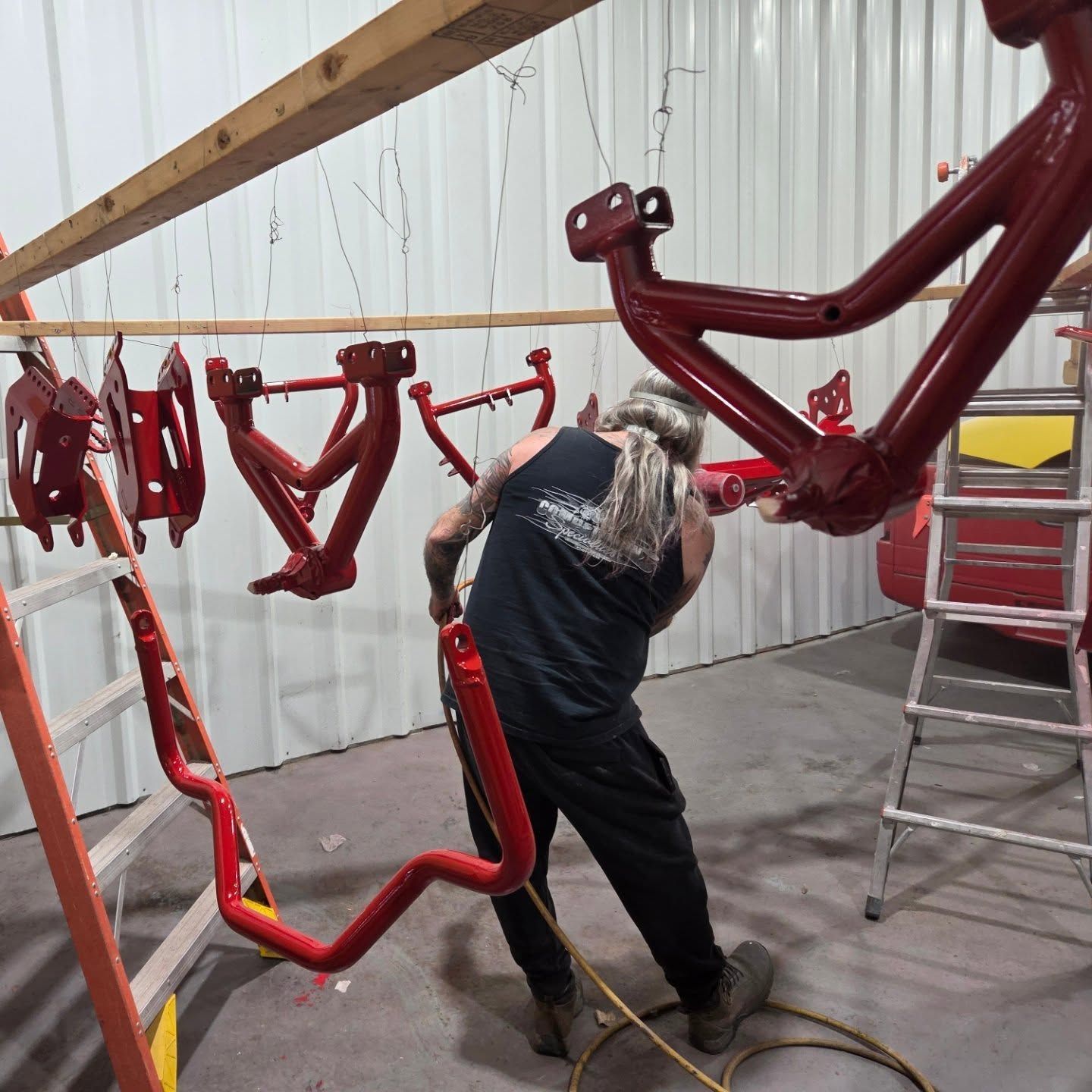A man is working on a red bicycle frame