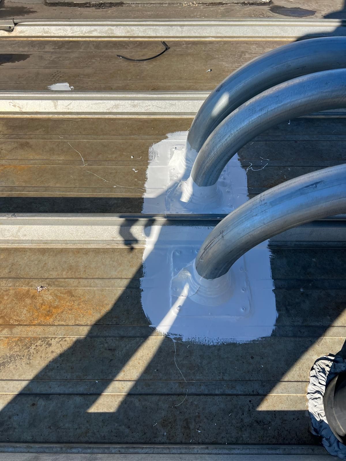 Person using a torch to apply sealant to a flat roof, near a wall. Person using a torch to apply sealant to a flat roof, near a wall.