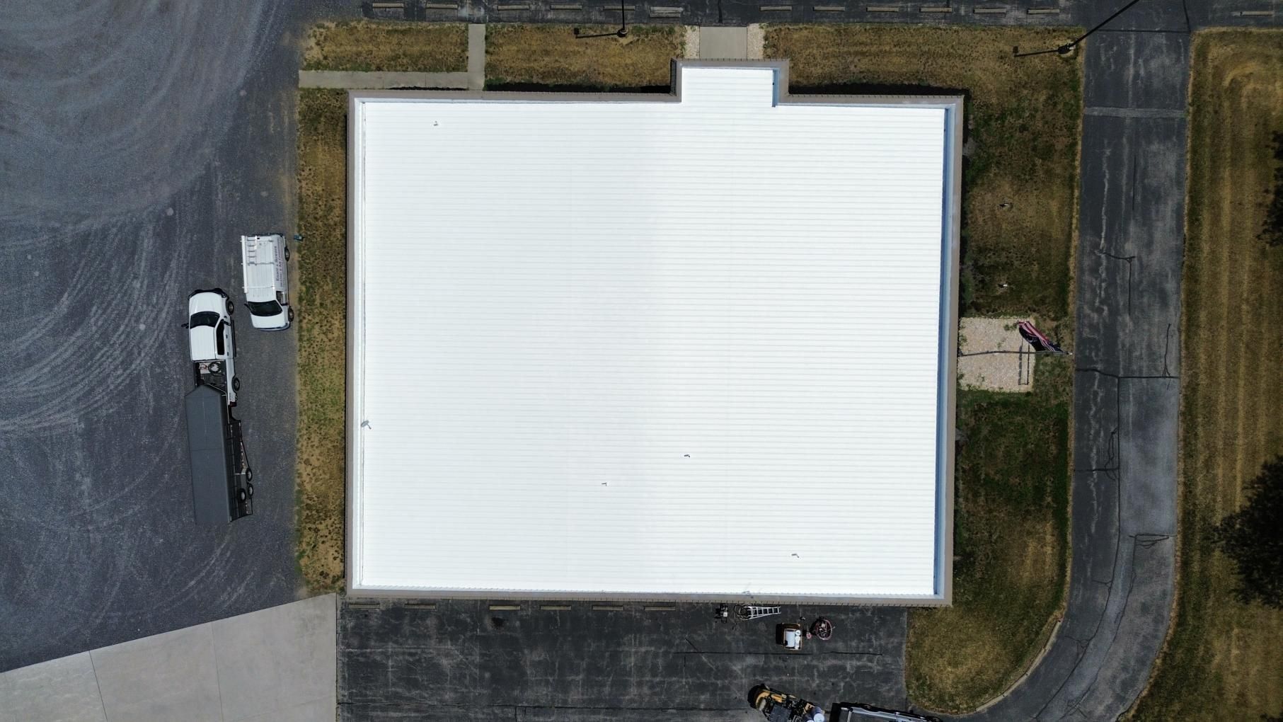 Two workers using a torch to apply black roofing material on a flat roof, wearing gloves and boots.