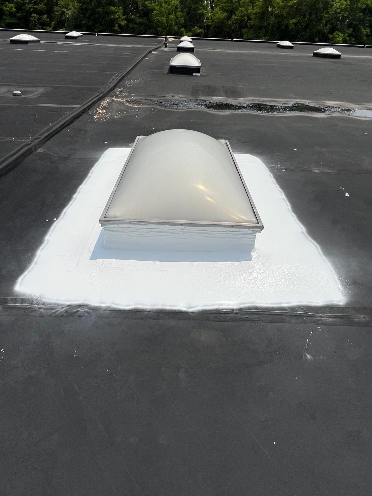Person using a heat gun and roller to seal a seam on a black flat roof. Person using a heat gun and roller to seal a seam on a black flat roof.