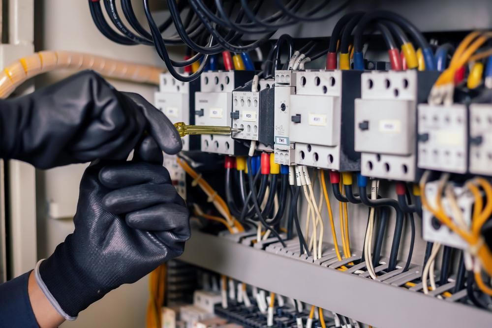 A Person Wearing Black Gloves Is Working on An Electrical Panel — Peter Gow Electrical in Bangalow, NSW