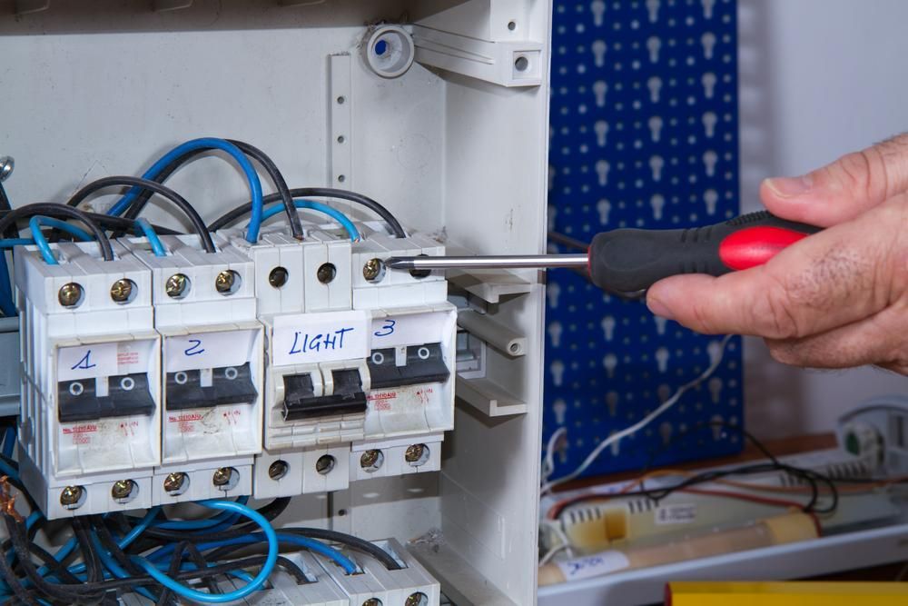 A Person Is Fixing an Electrical Box with A Screwdriver — Peter Gow Electrical in Lismore, NSW