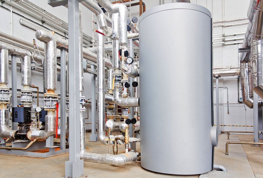 A Large Gray Tank Is Sitting in A Factory Surrounded by Pipes — Peter Gow Electrical in Lismore, NSW