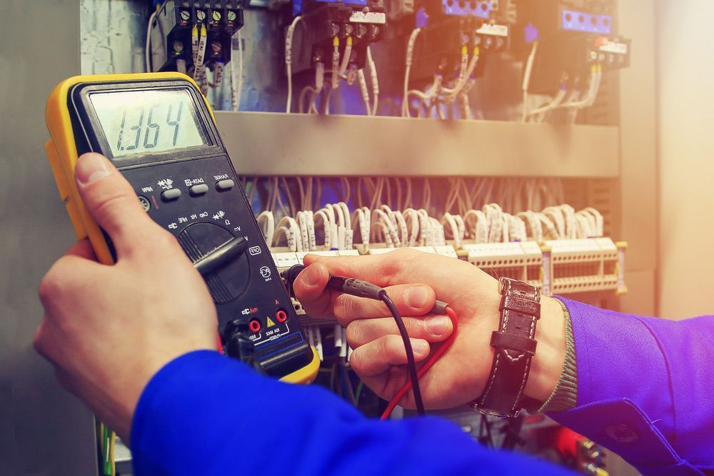 A Man Is Holding a Digital Multimeter in His Hands — Peter Gow Electrical in Lismore, NSW