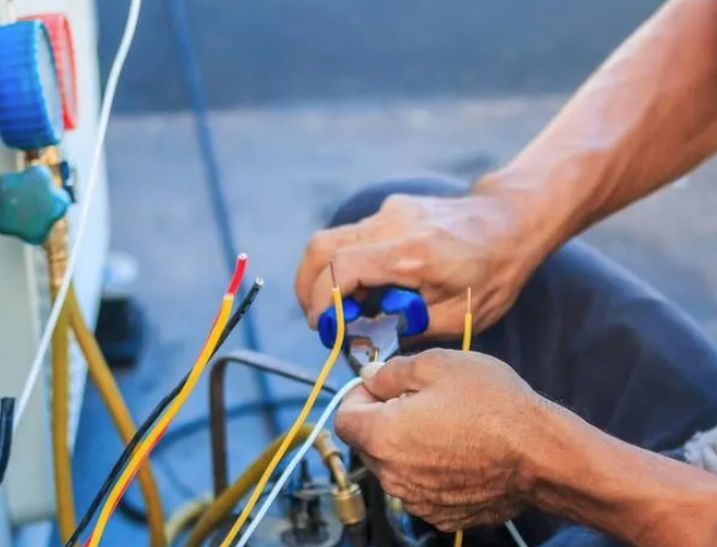 Level 2 electrician working on electrical wiring and service connections at an air conditioning unit