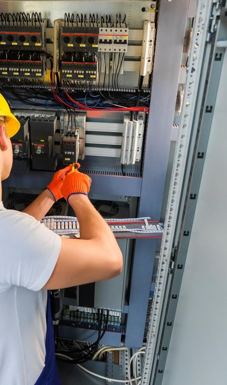 A Man Is Working on A Electrical Box with A Screwdriver — Peter Gow Electrical in Goonellabah, NSW