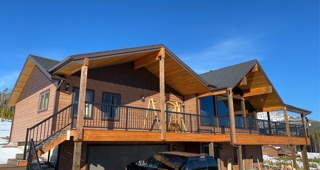 New construction two-story house with tan siding, a white garage door, and a concrete driveway under a blue sky.