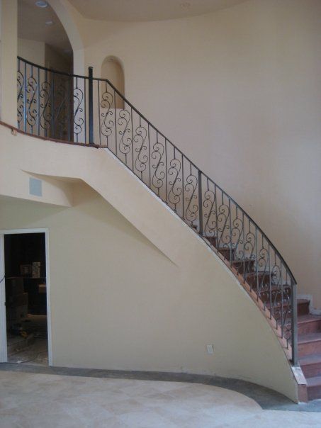 Staircase with ornate iron railing inside a beige building entryway