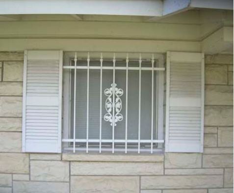 White barred window with shutters on a beige stone house exterior