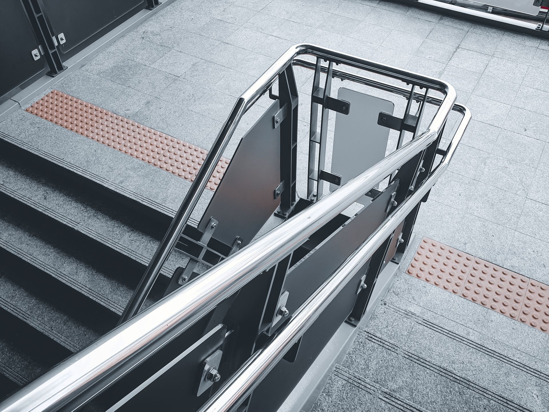 Staircase with a stainless steel railing and a central accessibility stairlift indoors
