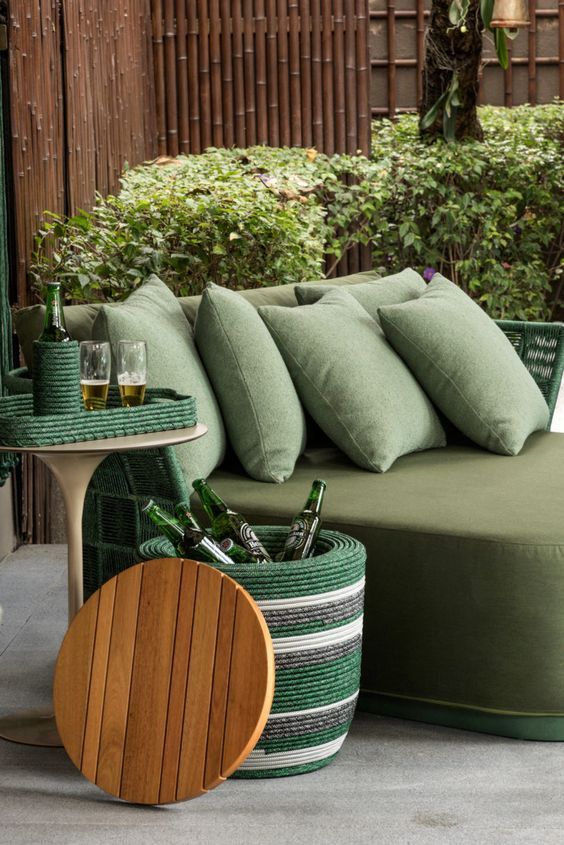 Um sofá com almofadas verdes e uma mesa de madeira ao lado.