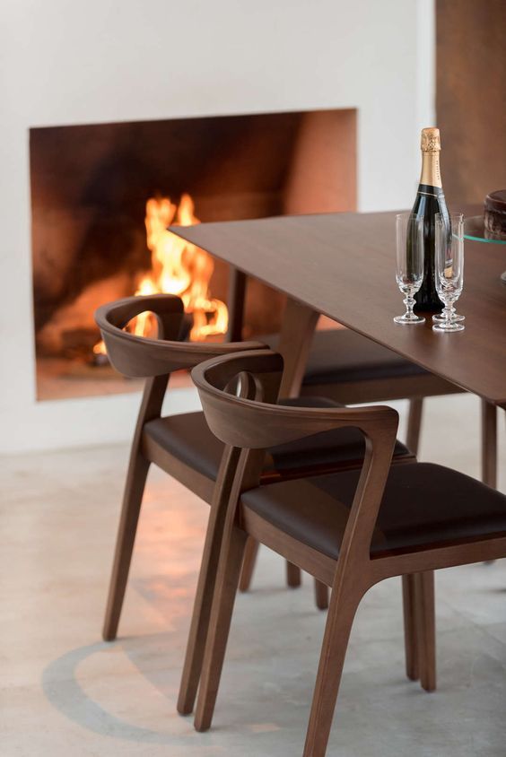 Uma mesa com uma garrafa de vinho e duas taças em frente a uma lareira.