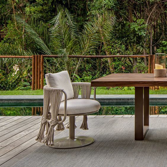 Uma cadeira está ao lado de uma mesa em um deck próximo a uma piscina.
